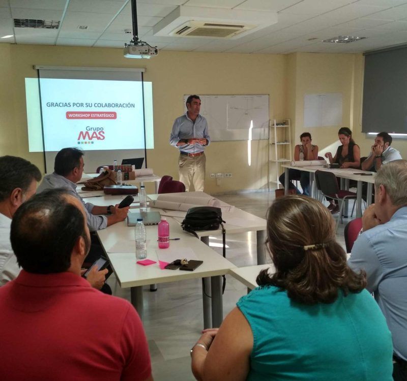 Formador impartiendo una sesión de sostenibilidad y ESG a directivos de empresa en un aula moderna.